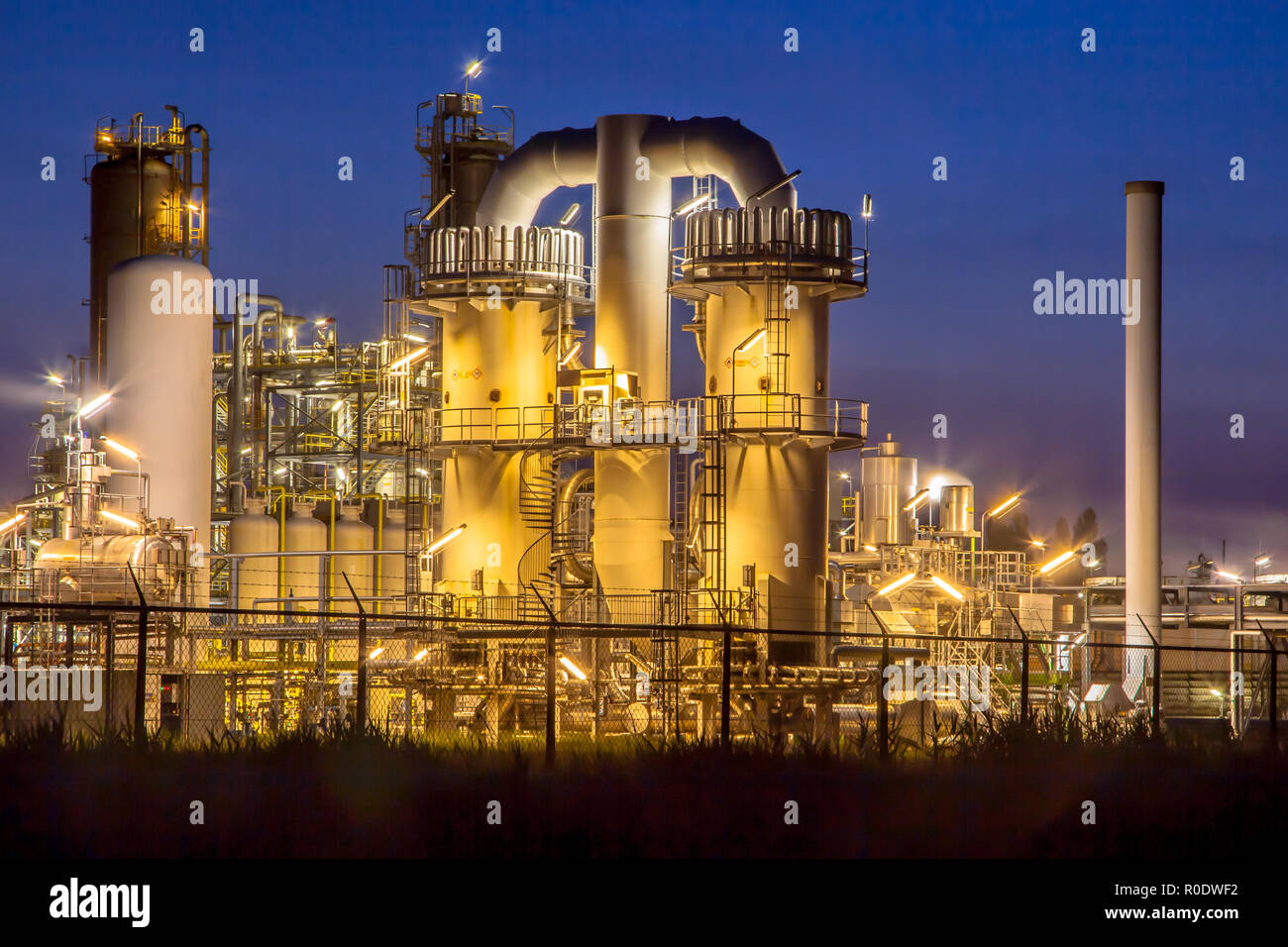 Détail d'une installation industrielle chimique lourde avec mazework de tuyaux dans le crépuscule de scène de nuit Banque D'Images