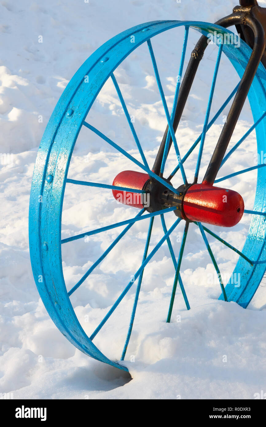 Détail peint métallique sous la forme d'une roue de vélo dans la neige en hiver à l'extérieur Banque D'Images