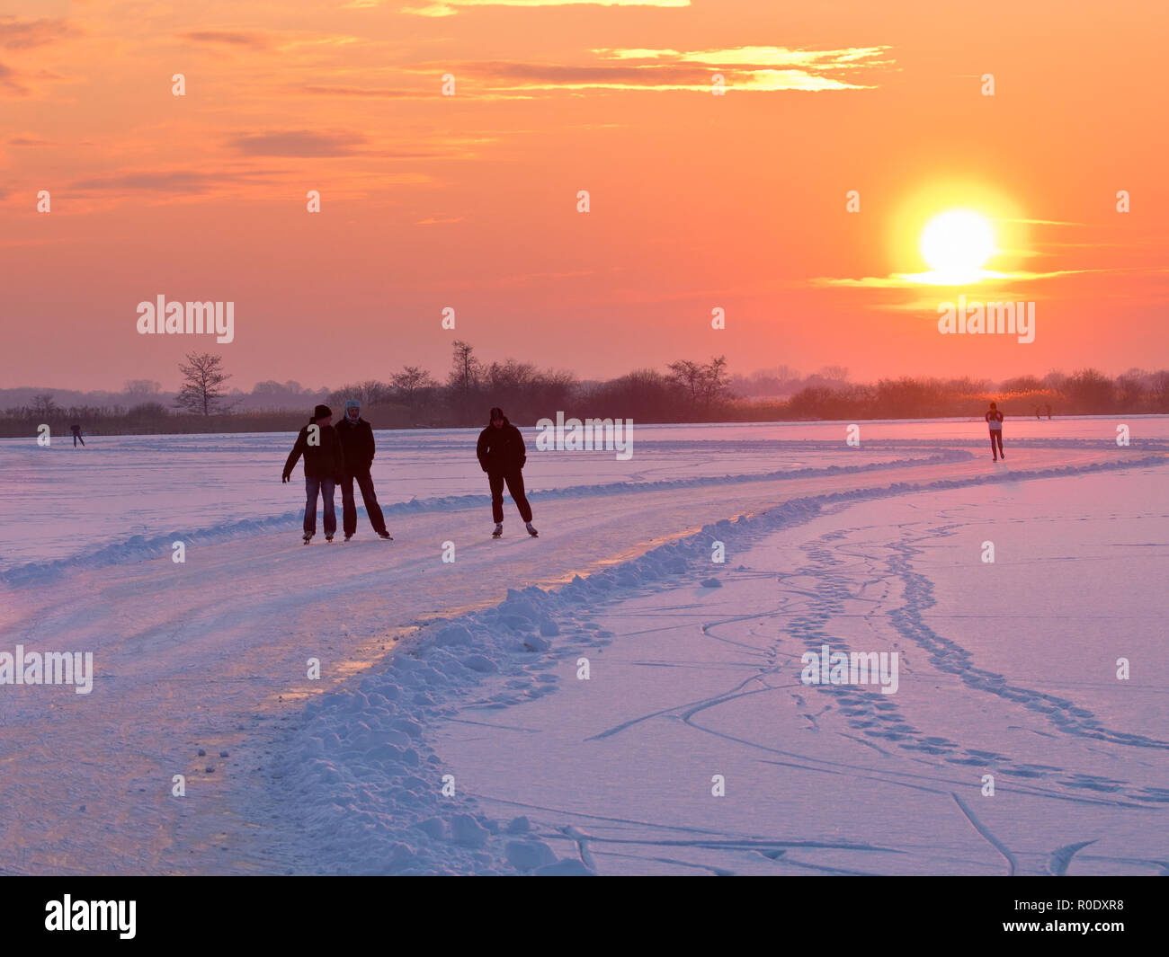 Groupe de patineurs sur glace naturelle pendant le coucher du soleil Banque D'Images