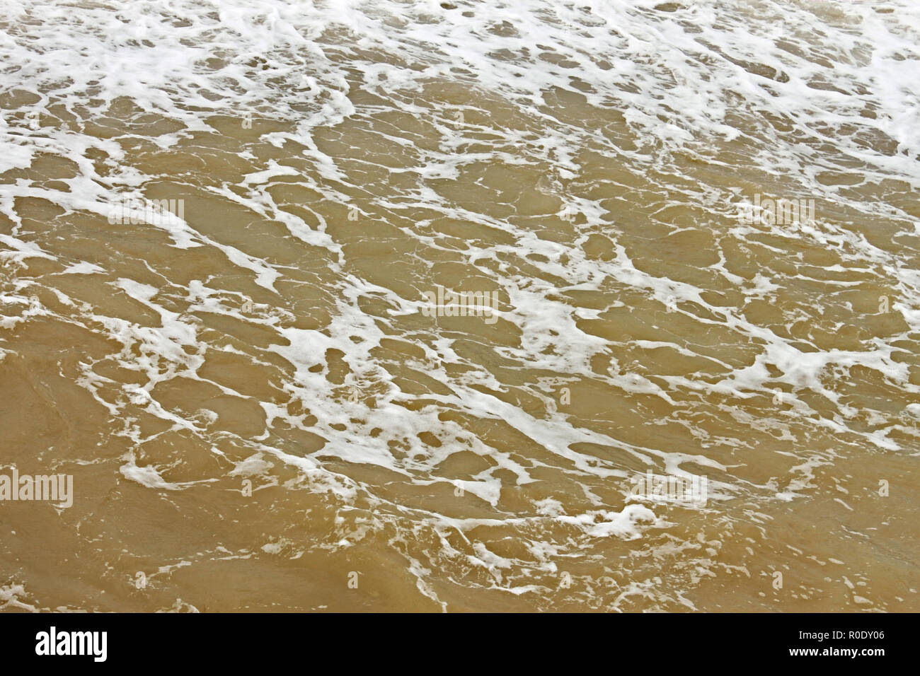 La surface de l'eau mousseuse côtières après la tempête par dragage des fonds marins pollués sand Banque D'Images