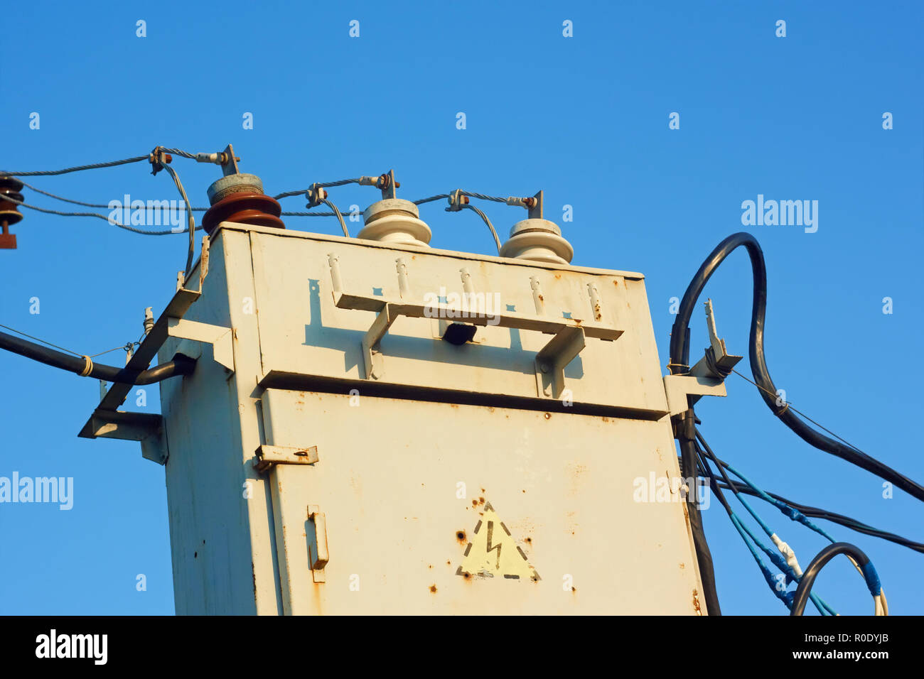 Ancien transformateur avec isolant et des fils sur un fond de ciel bleu azur Banque D'Images