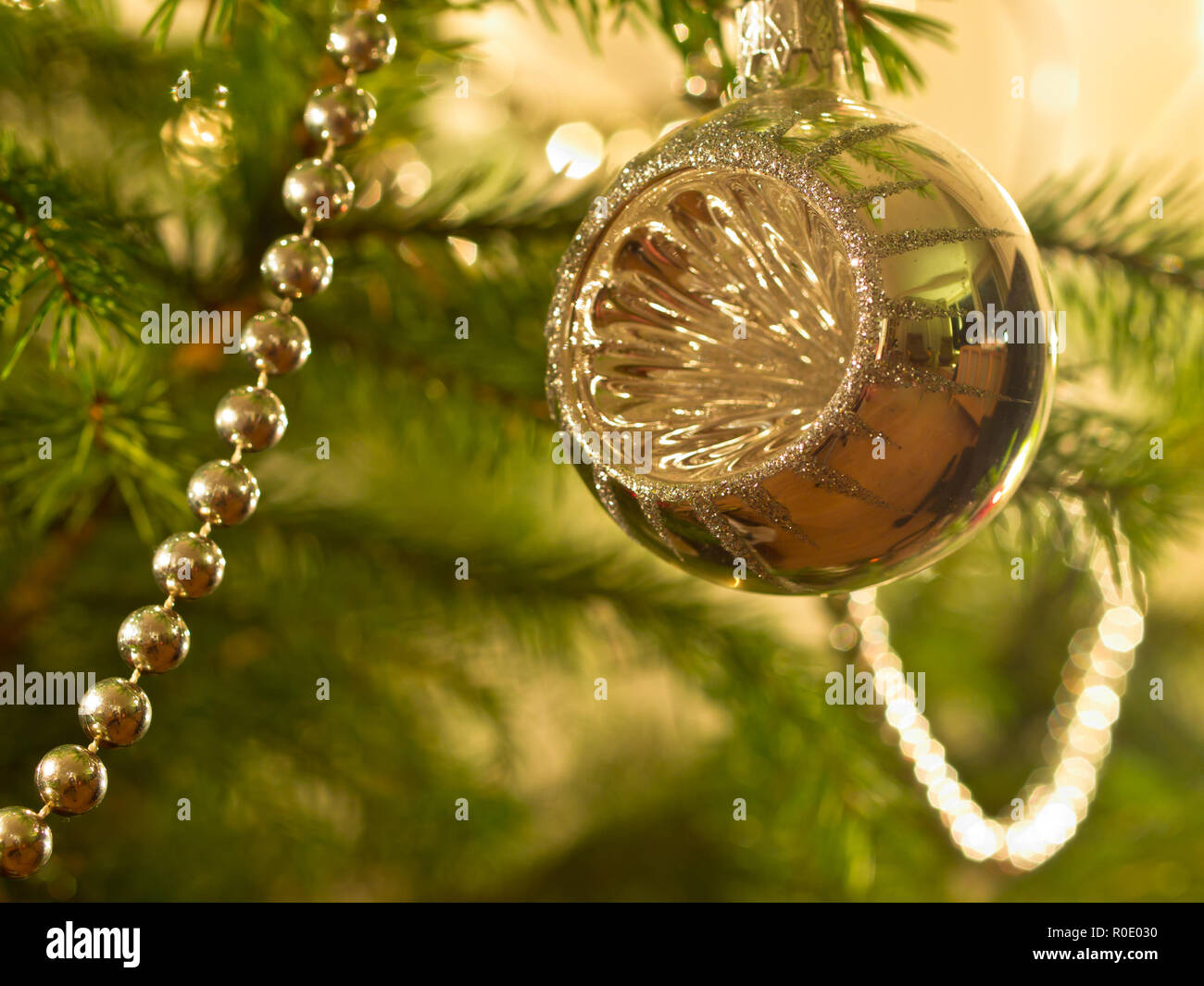 Een zilveren kerstbal hangt een boom verlichte Banque D'Images