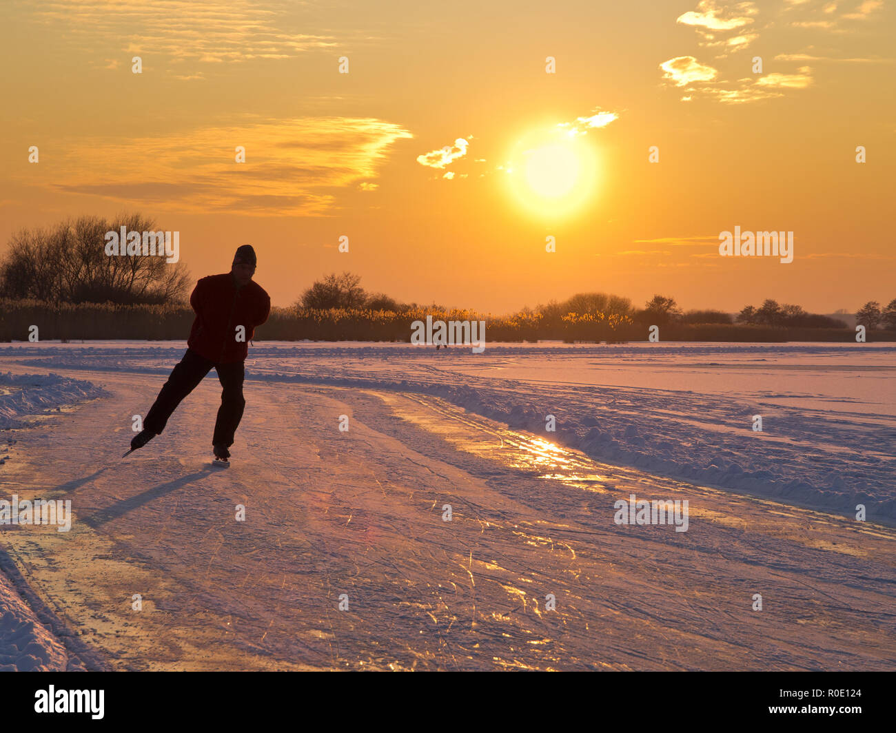 Un patinage sur glace est aproaching pendant le coucher du soleil Banque D'Images
