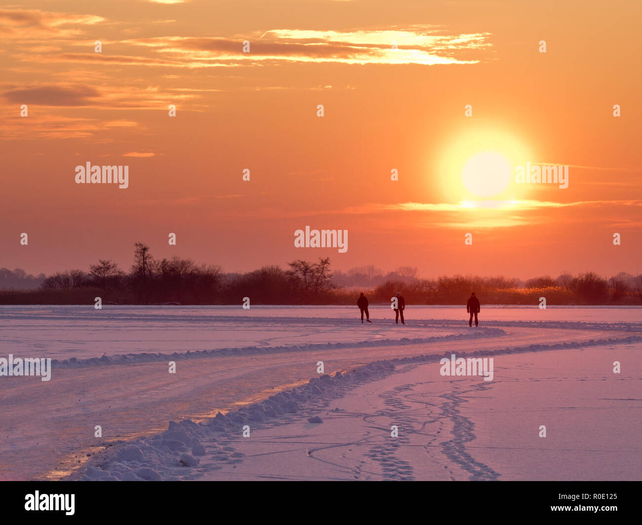 Patineurs de vitesse sont aproaching tandis que le soleil se couche sur le lac en hiver néerlandais Banque D'Images
