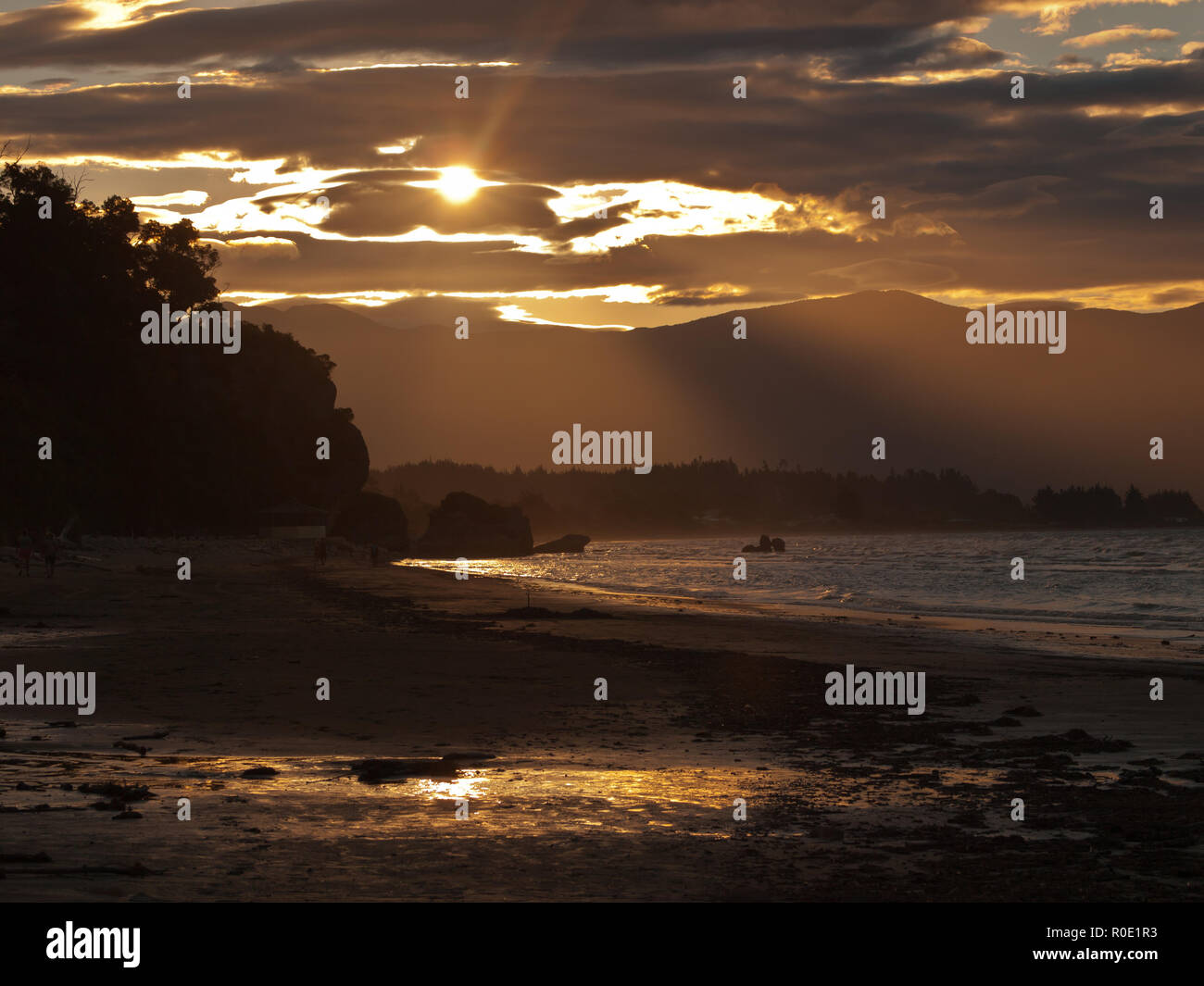Un beau coucher du soleil doré sur une plage de sable à pakawau Nouvelle-Zélande Banque D'Images
