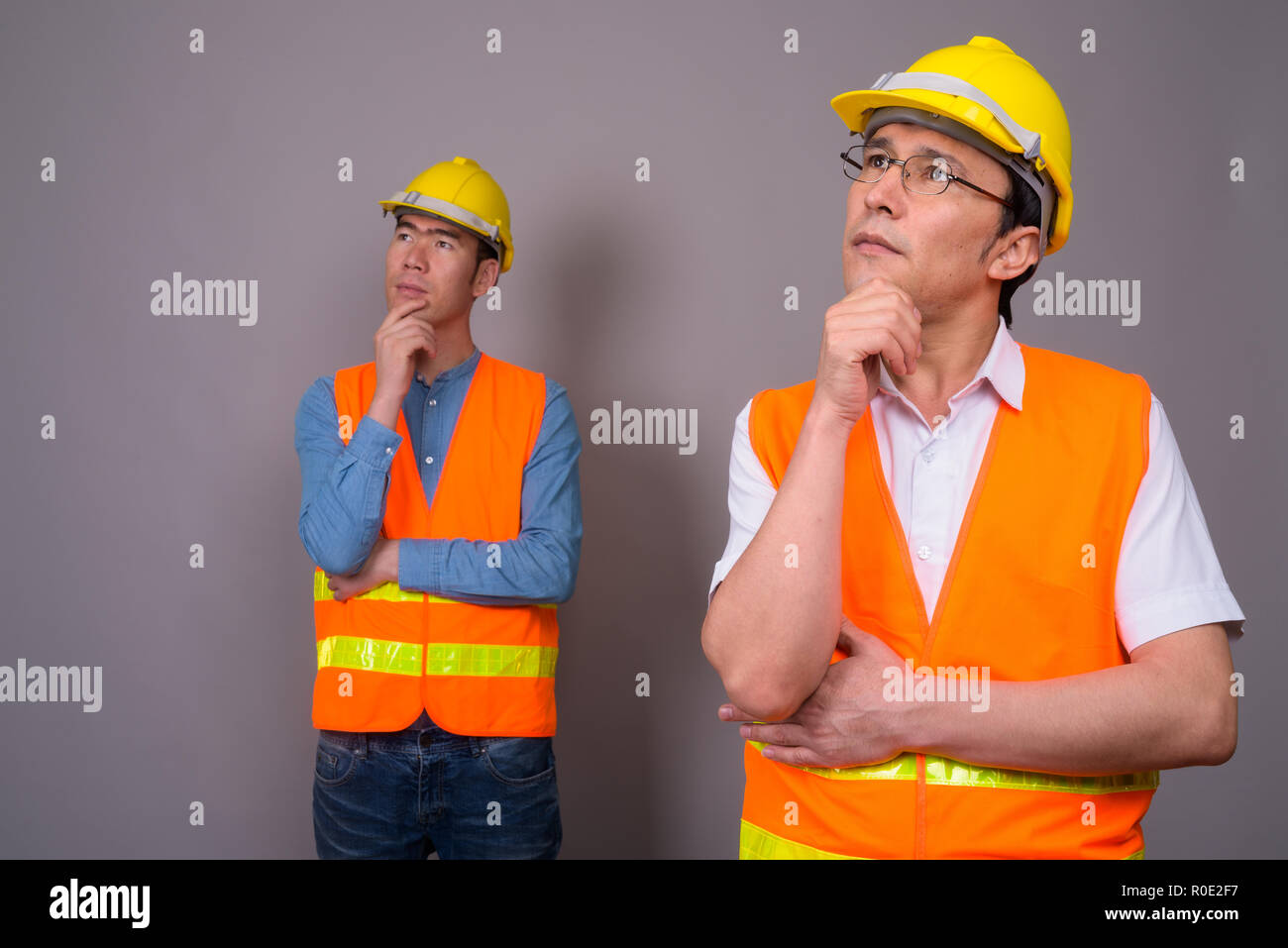 Deux jeunes hommes asiatiques construction worker ensemble contre ba gris Banque D'Images