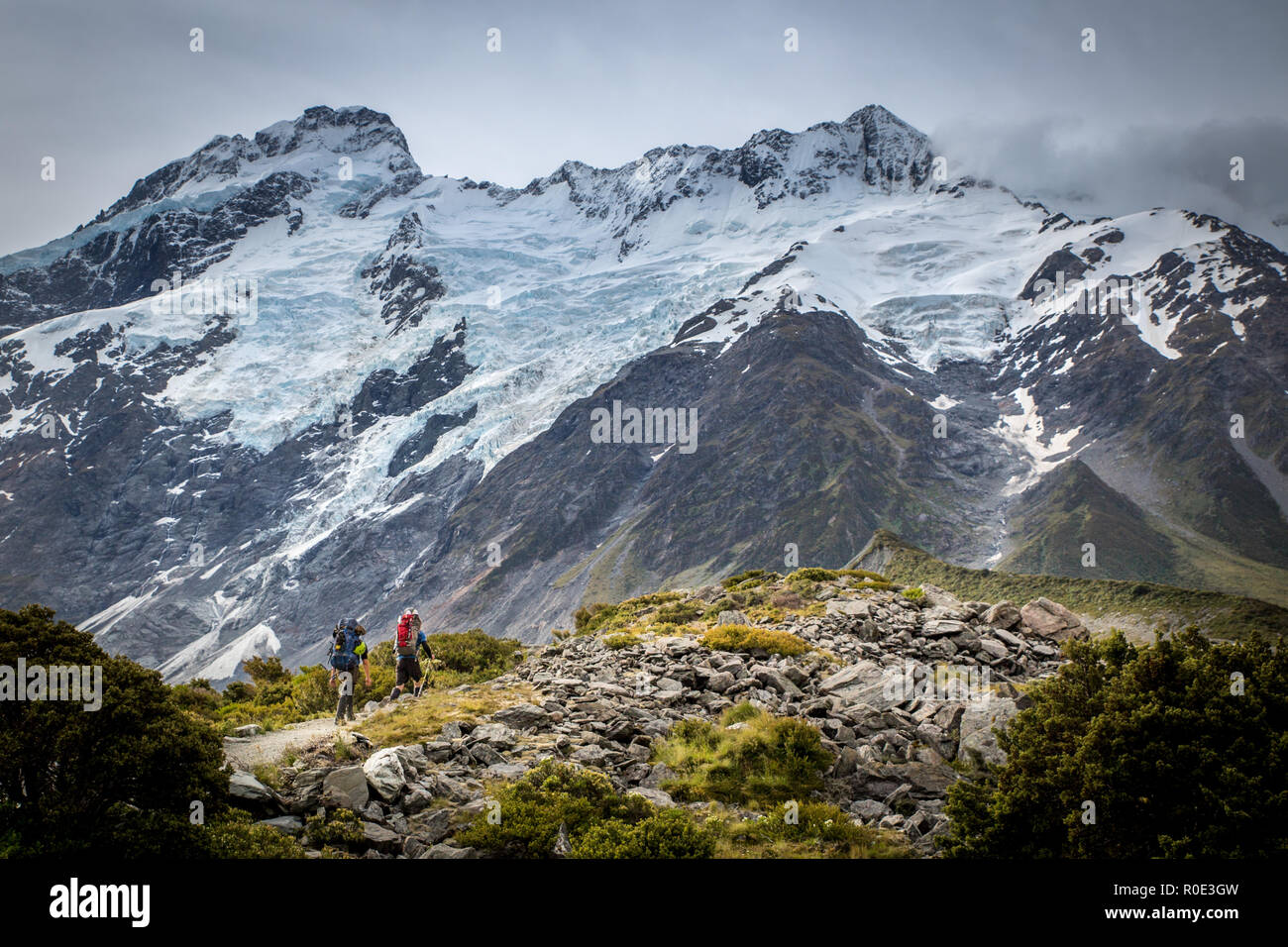 Deux alpinistes la tête de la piste vers les montagnes dans le parc national à Mt Cook, Nouvelle-Zélande Banque D'Images