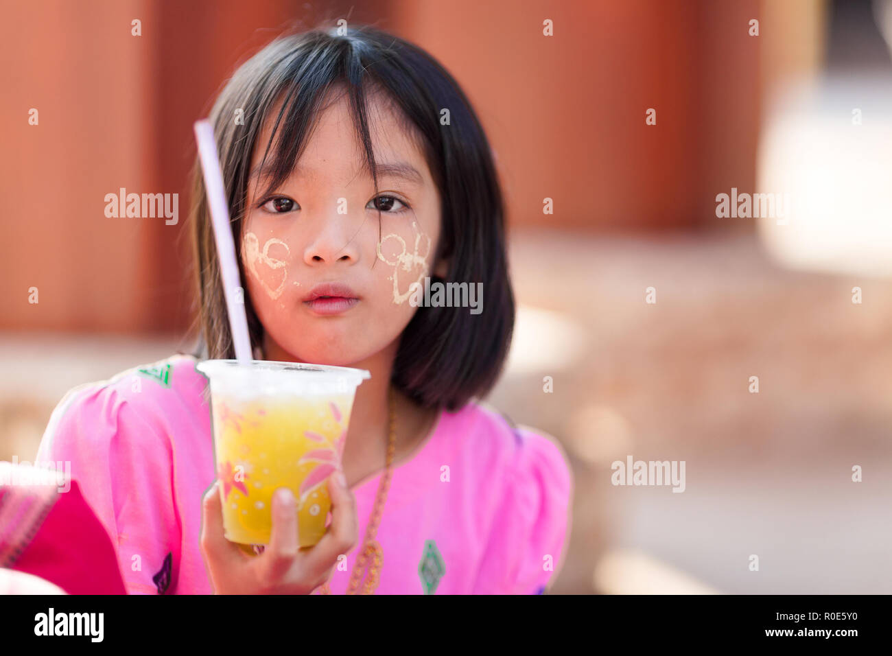 SANGKHLABURI, Thaïlande, le 24 janvier 2016 : Une petite fille tenant un soda est posant près d'un temple en Sanghlaburi, Thaïlande Banque D'Images