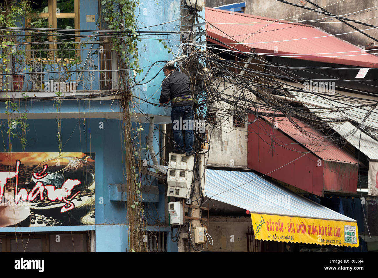 HANOI, Vietnam, 16 décembre 2014 : Un technicien debout sur une échelle est la réparation du réseau électrique en désordre à Hanoi, Vietnam Banque D'Images