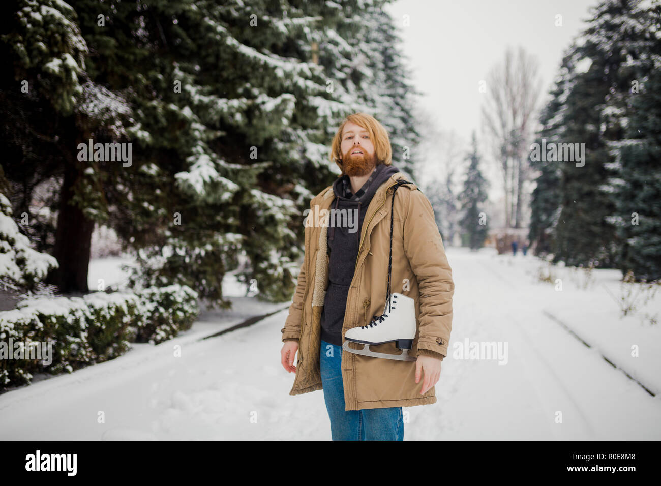 Thème Sports d'hiver. Portrait. Beau jeune homme de race blanche avec de longs cheveux et barbe rouge. En hiver pose modèle snow park contre l'arrière-plan de la fo Banque D'Images