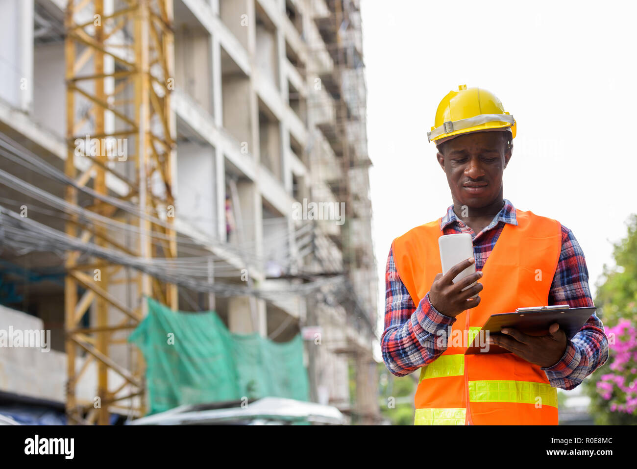 Young black African man construction worker lecture le presse-papiers Banque D'Images