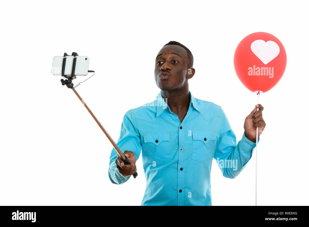 Studio shot of young black African man holding red balloon avec Banque D'Images