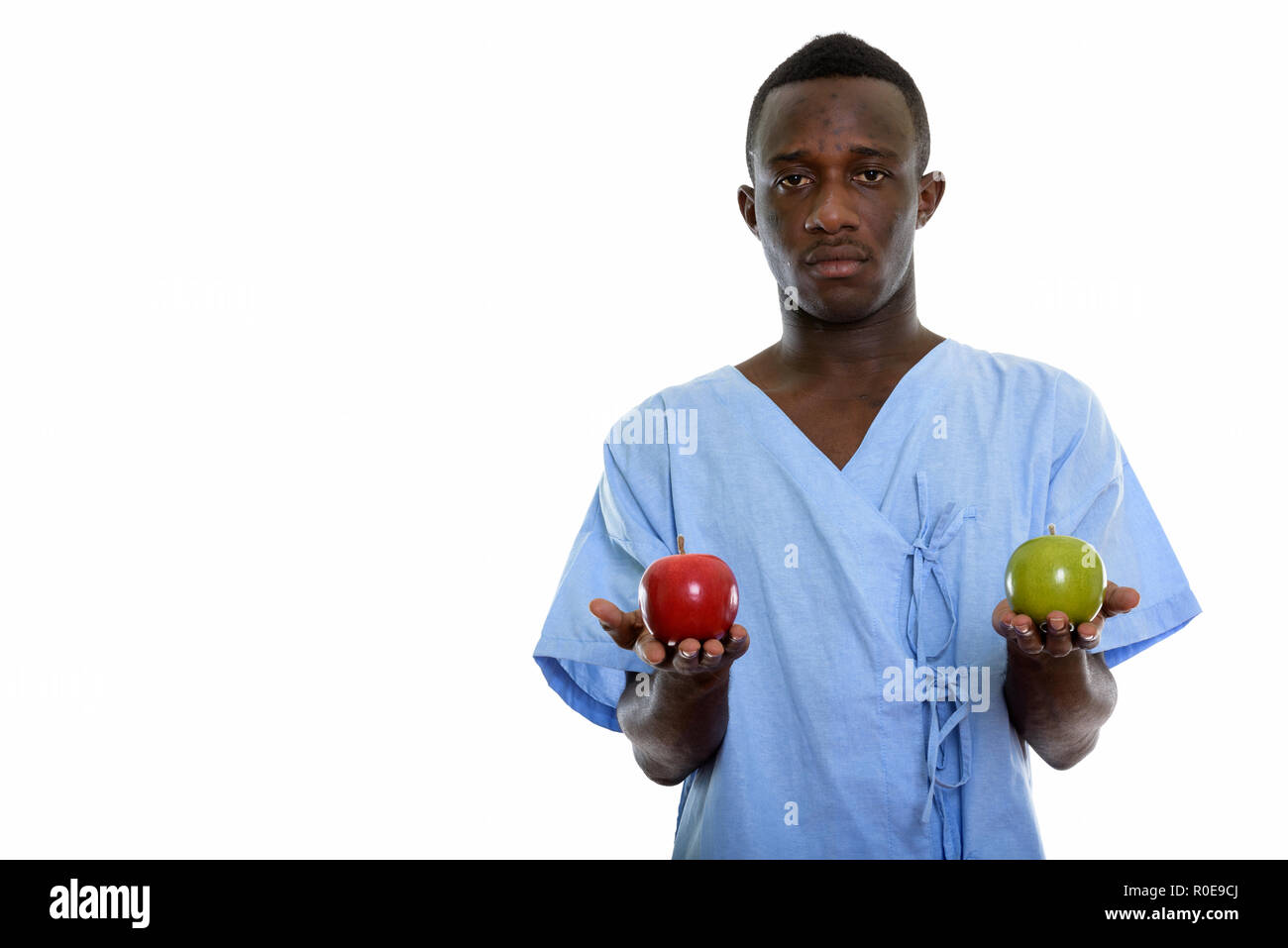 Studio shot of young black African man holding red apple patient Banque D'Images