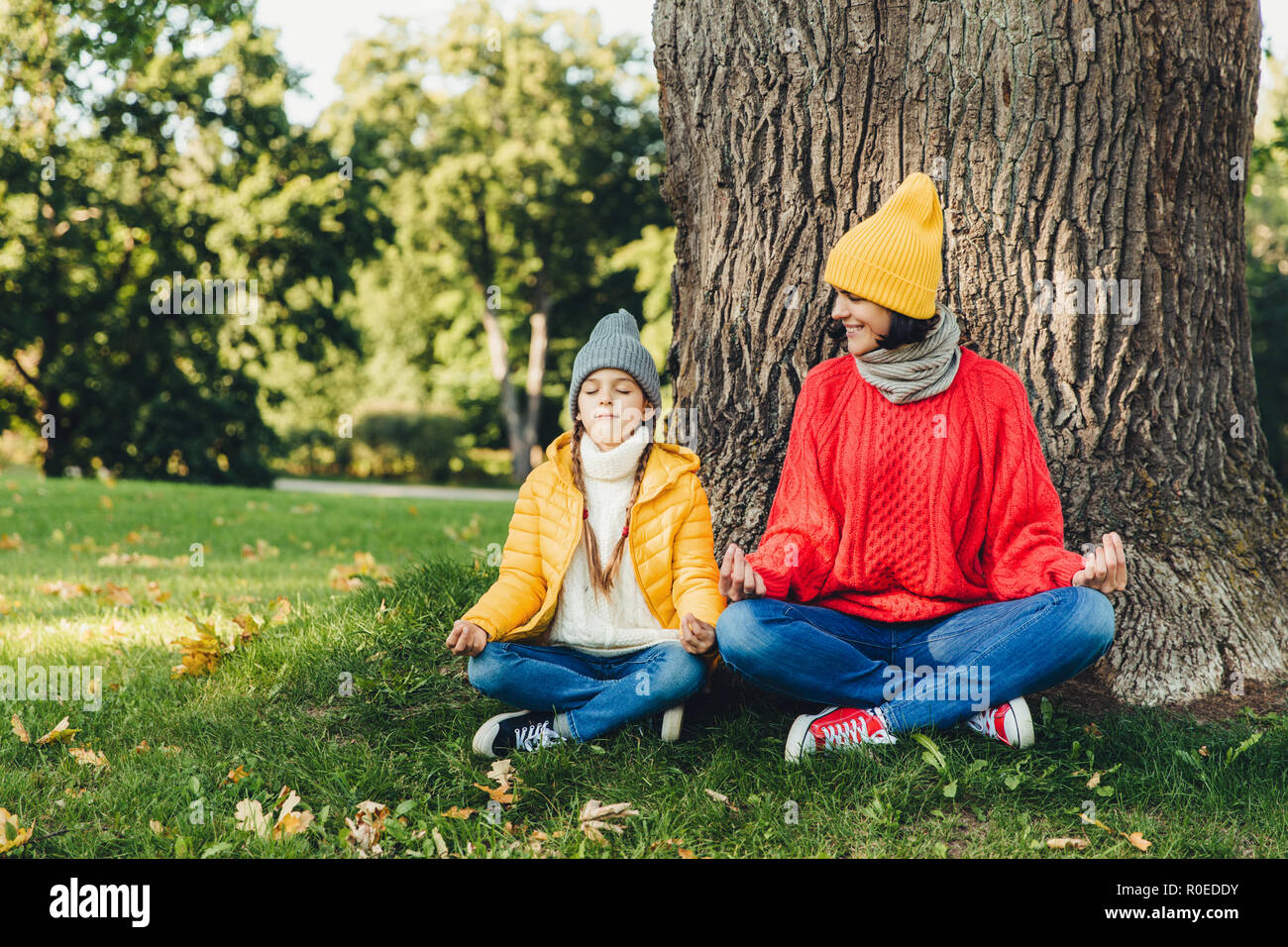 Le langage du corps concept. Petit enfant insouciant se trouve près de sa belle mère, garder les mains en signe mudra, gardez les yeux fermés, essayez de calmer après dur wor Banque D'Images