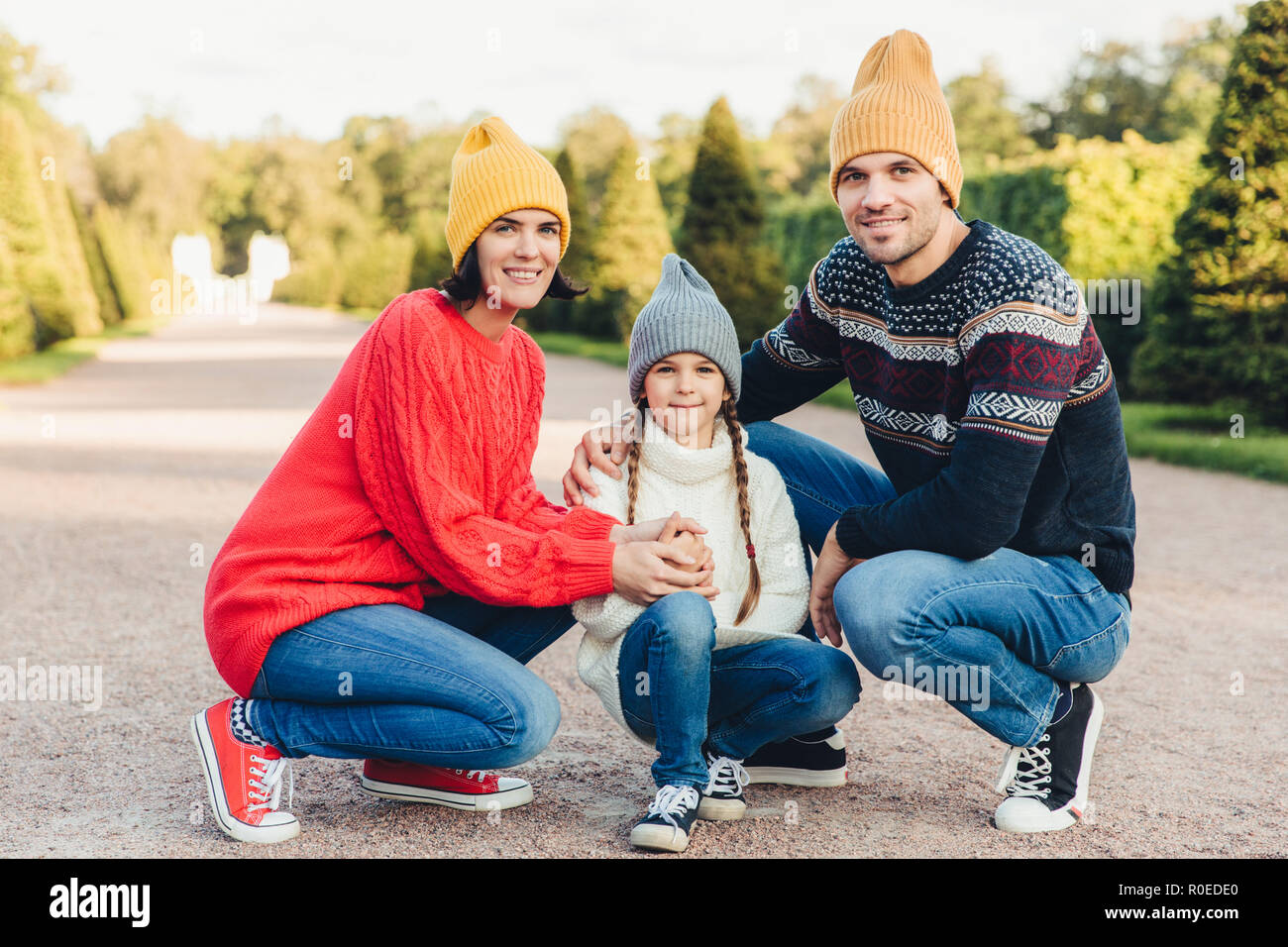 Porter des vêtements en bonneterie, conviviale et familiale, ont marcher ensemble, admirer l'automne splendide météo. Les jeunes parents affectueux et leur petite fille mignonne pl Banque D'Images