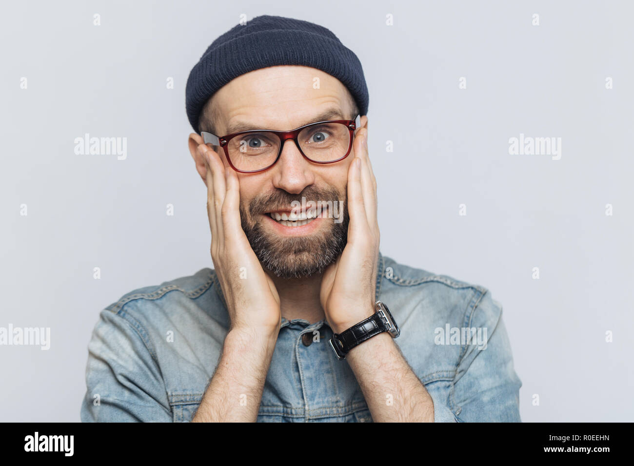 Portrait of attractive young avec une épaisseur de l'homme regarde avec barbe et moustache heureuse expression, a white perfect dents, poses en studio contre blank Banque D'Images