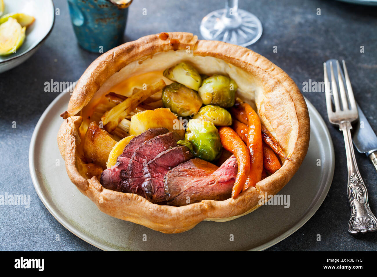 Dîner rôti de boeuf, carottes, choux de Bruxelles dans la région de yorkshire pudding géant Banque D'Images