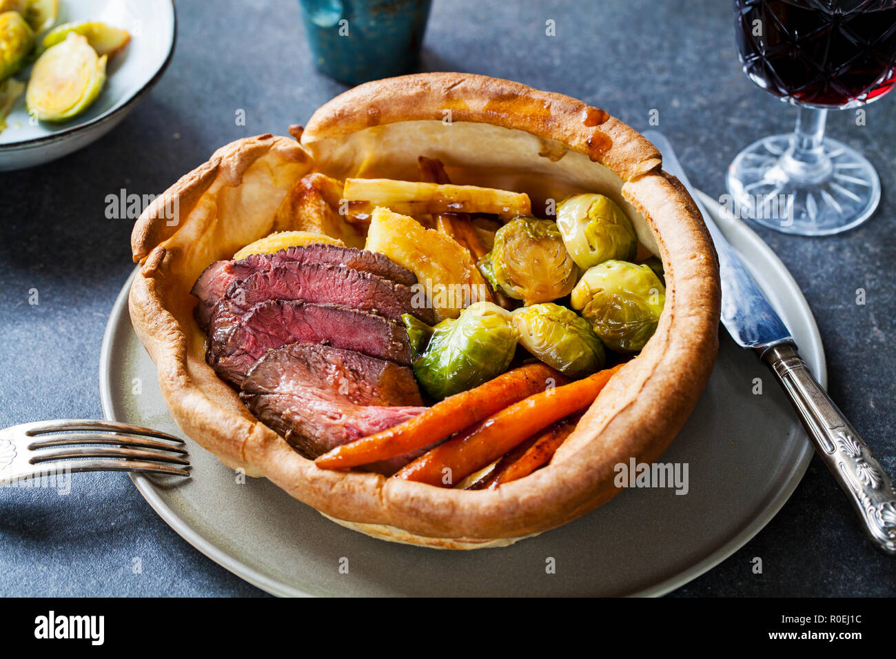 Dîner rôti de boeuf, carottes, choux de Bruxelles dans la région de yorkshire pudding géant Banque D'Images
