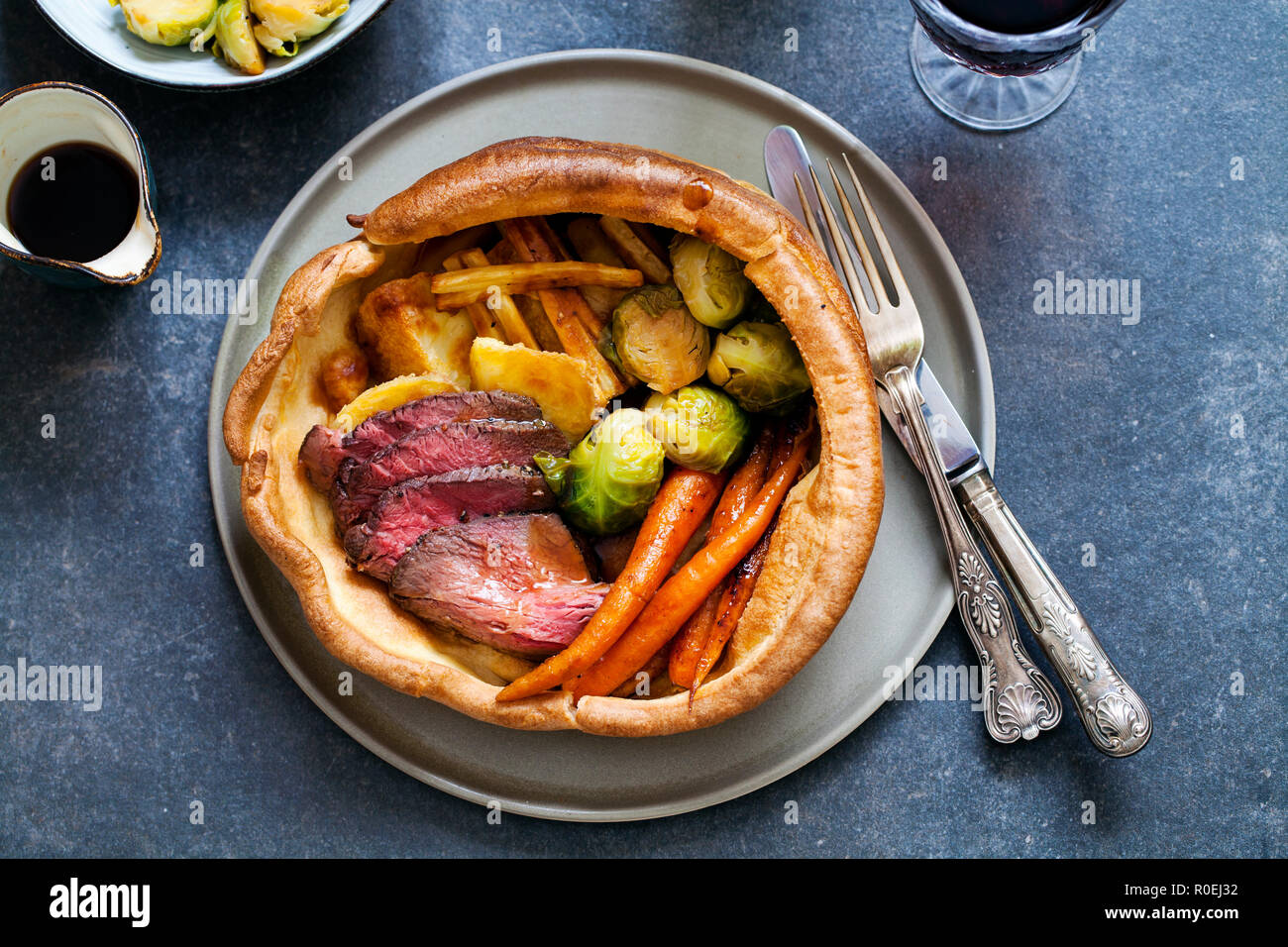 Dîner rôti de boeuf, carottes, choux de Bruxelles dans la région de yorkshire pudding géant Banque D'Images