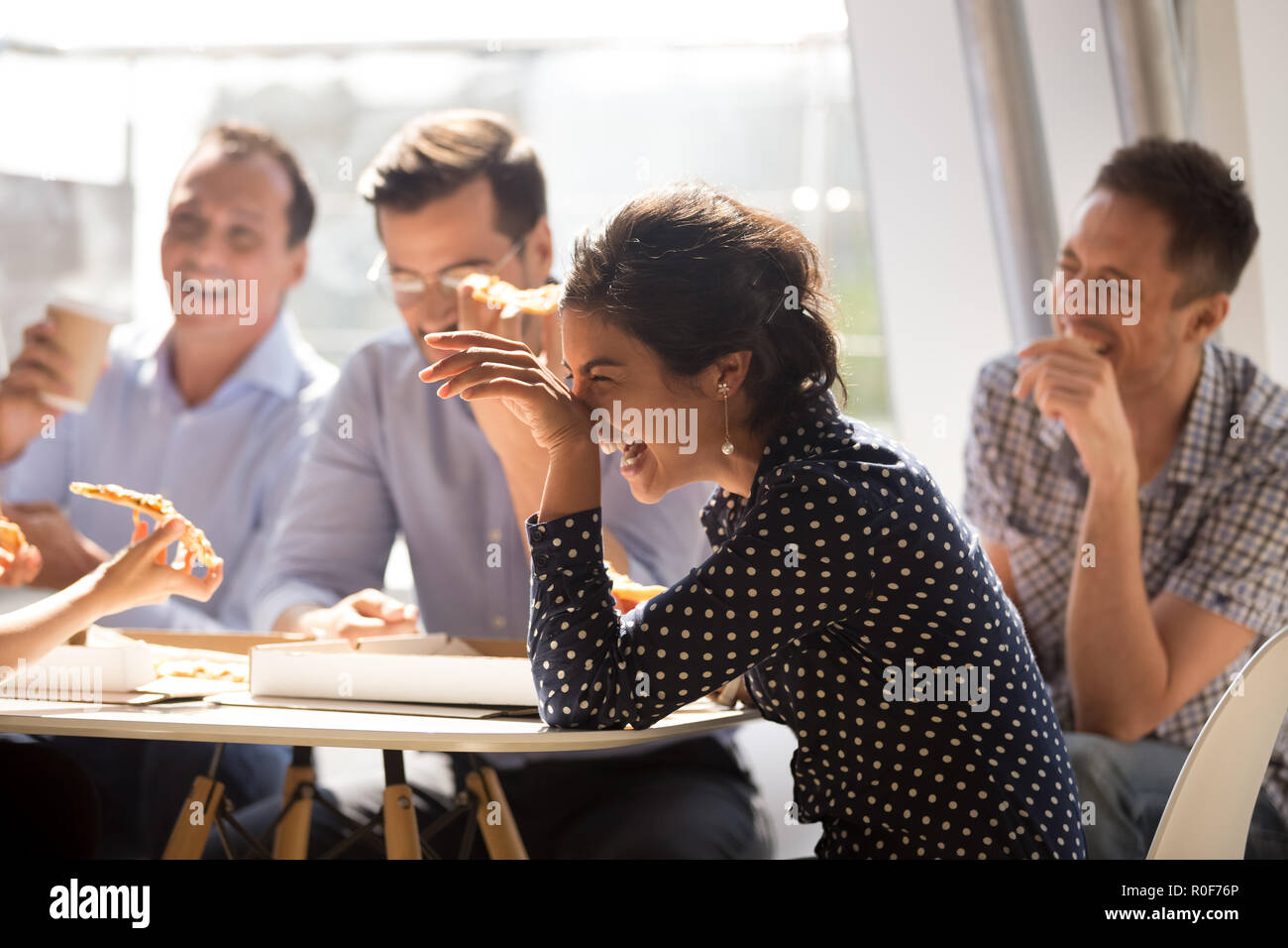 Indian woman laughing eating pizza avec divers collaborateurs en off Banque D'Images