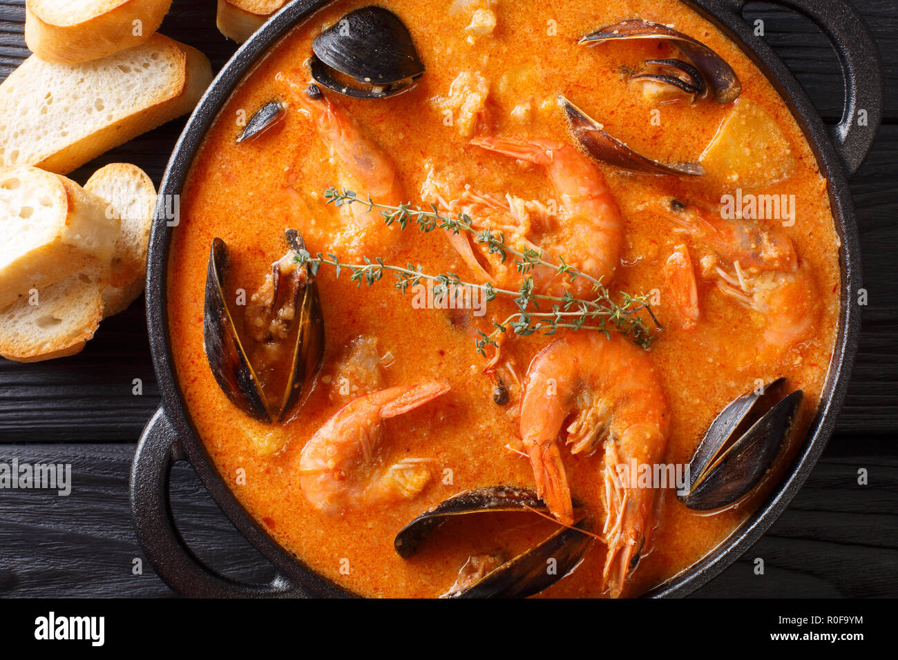 L'Espagnol Suquet de Peix soupe aux fruits de mer, pommes de terre, les herbes et le poisson close-up dans une casserole sur la table. Haut horizontale Vue de dessus Banque D'Images