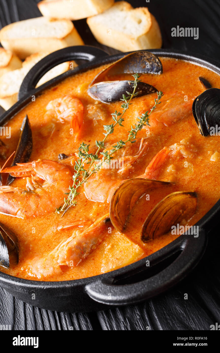 Suquet de Peix soupe aux fruits de mer, pommes de terre, les herbes et le poisson assaisonné avec picada close-up dans une casserole sur la table verticale. Banque D'Images