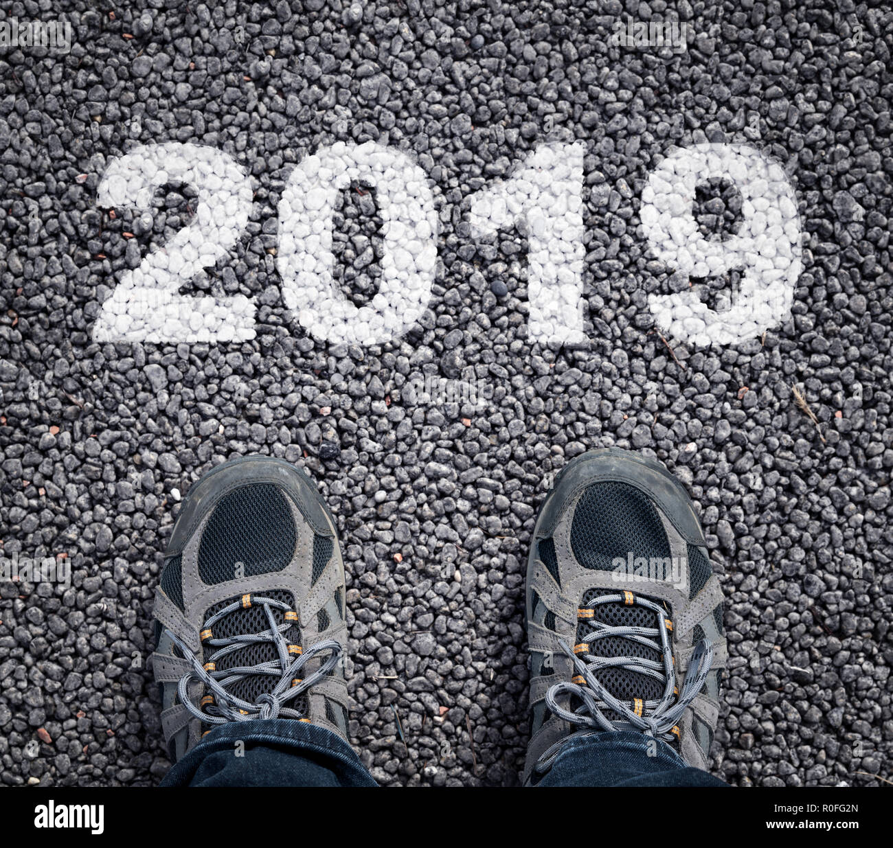 Bonne année 2019. homme jambes dans sneakers debout sur route asphaltée et le numéro 2019. Banque D'Images