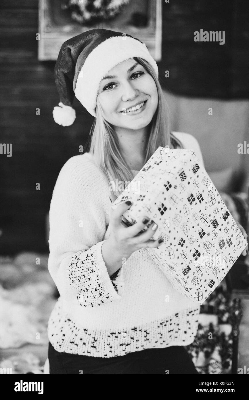 Happy woman in santa hat holding present fort. Banque D'Images