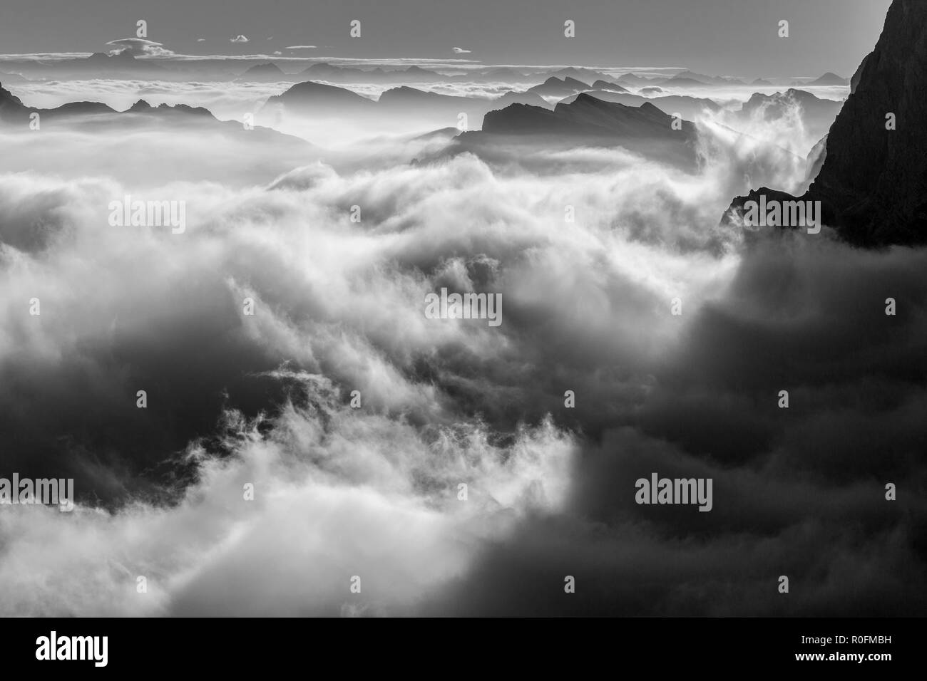 Nuages en mouvement au-dessus de la vallée au lever du soleil. Marée évocatrice de nuages. Paysage de montagne noir et blanc. Les Dolomites. Alpes italiennes. Europe. Banque D'Images