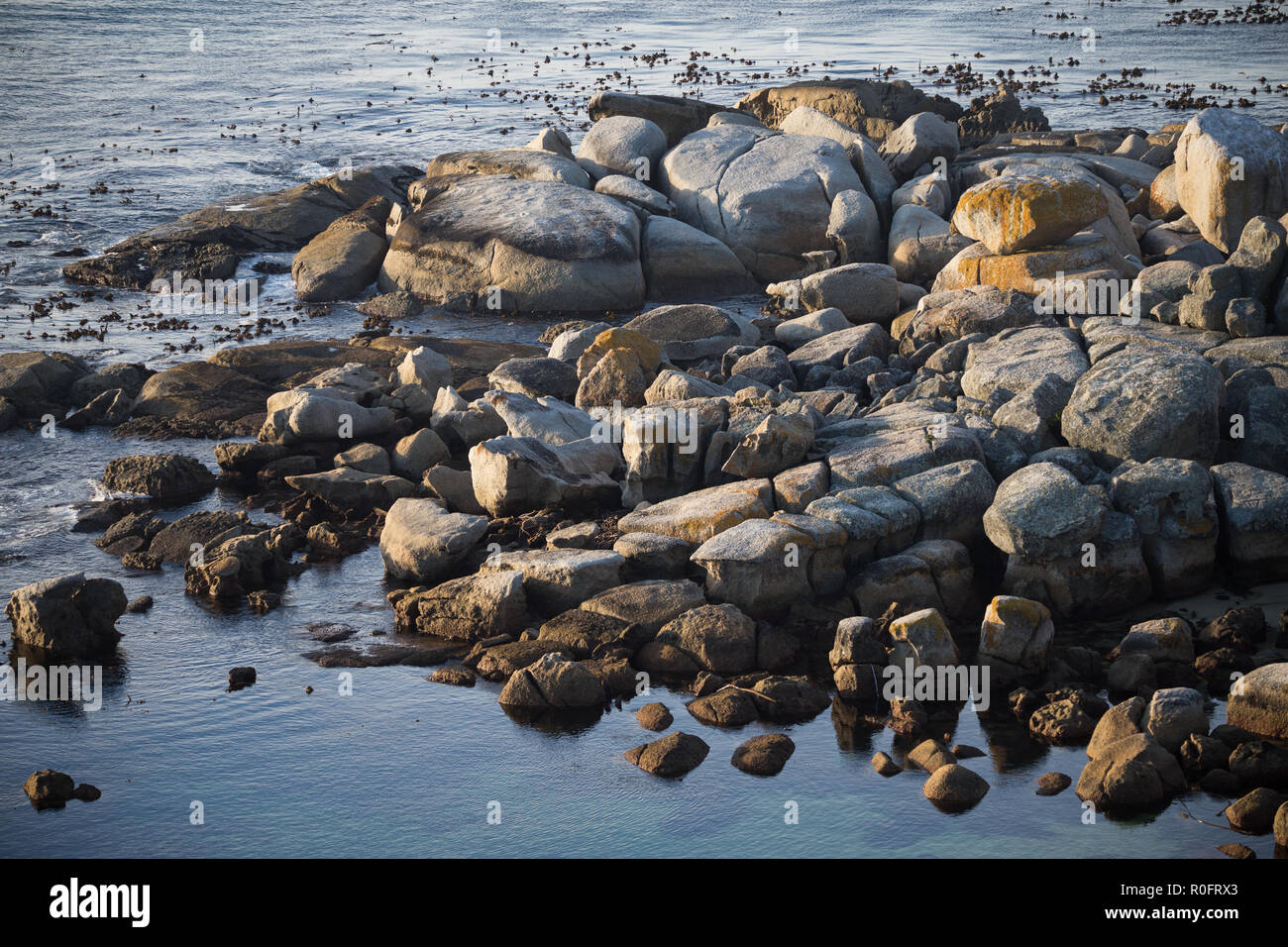 Les petites roches et les rochers entourés par l'océan Atlantique au coucher du soleil sur la côte de Cape Town, en Afrique du Sud pendant le coucher du soleil Banque D'Images