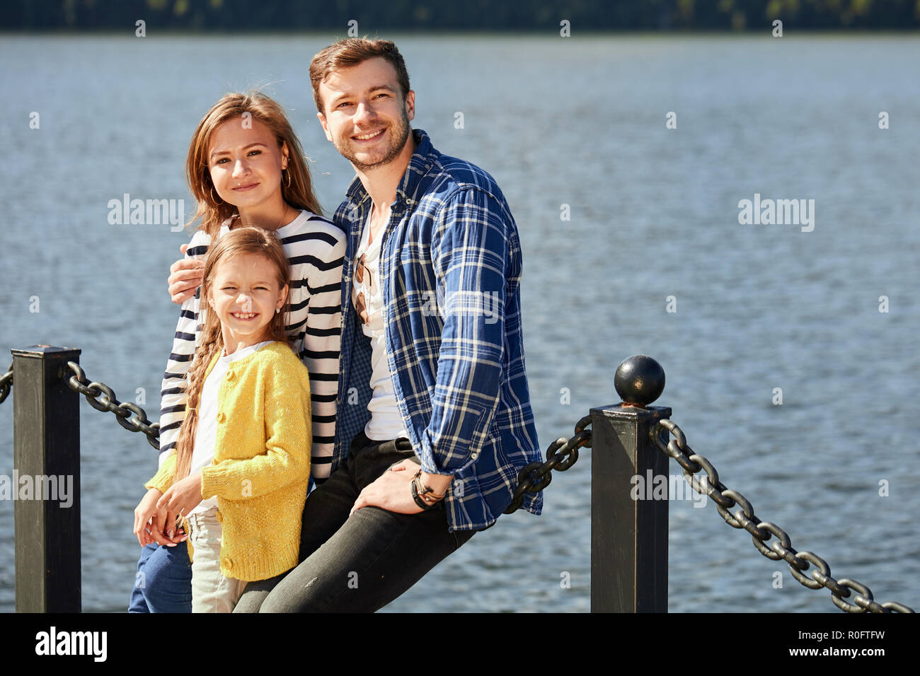 Happy Family looking at camera tout en se posant sur une jetée à lac tranquille Banque D'Images