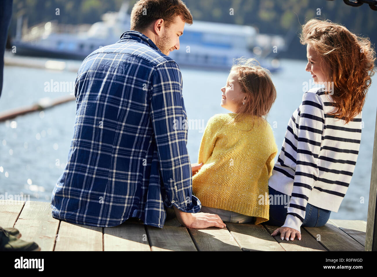 Vue arrière du siège de la famille sur la jetée dans la journée d'automne. Portrait de famille de l'automne Banque D'Images