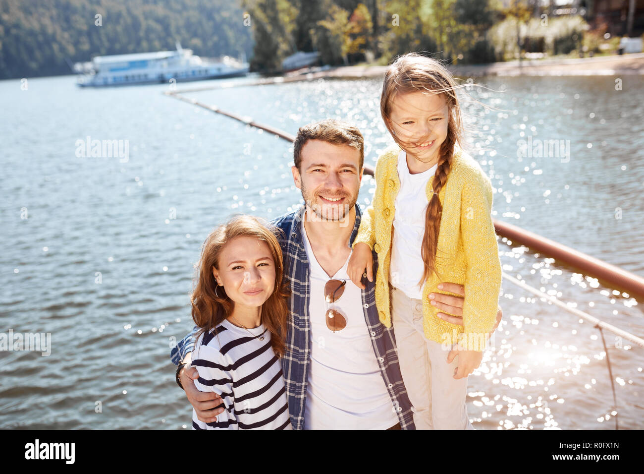 Happy Family looking at camera tout en se posant sur une jetée à lac tranquille Banque D'Images