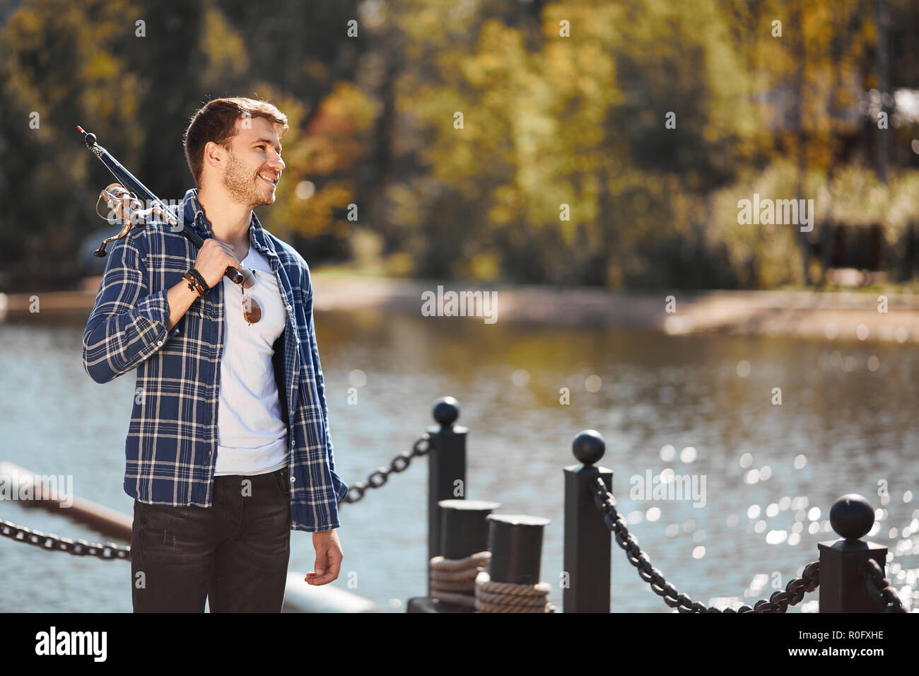 Jeune pêcheur avec rod et lunettes de la pêche dans le lac Banque D'Images