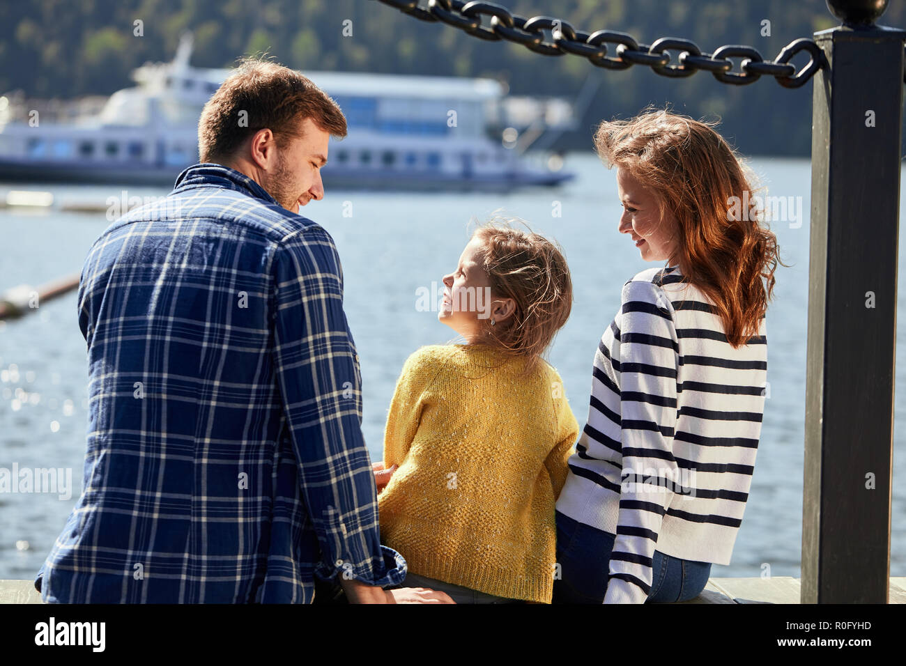Vue arrière du siège de la famille sur la jetée dans la journée d'automne. Portrait de famille de l'automne Banque D'Images