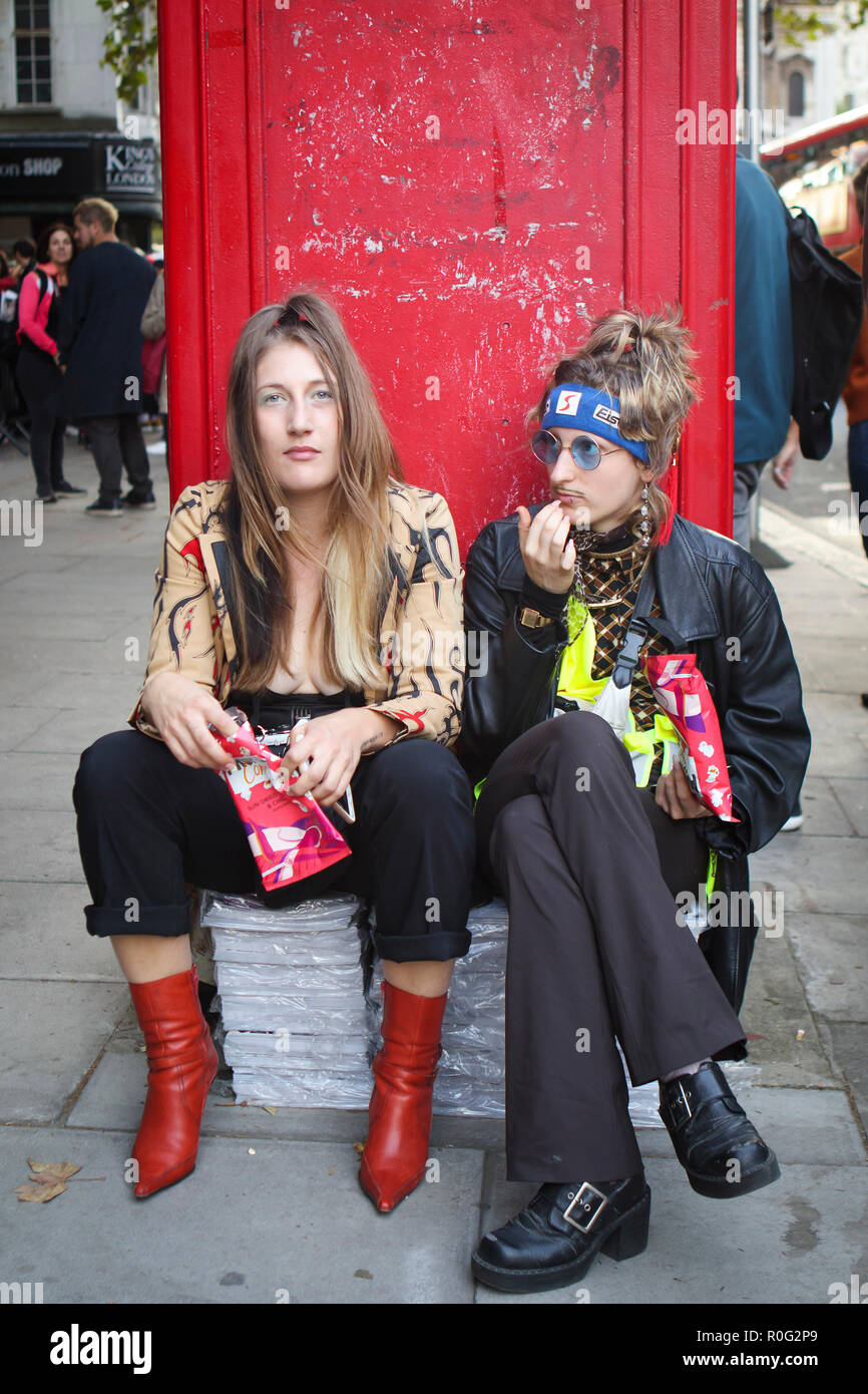 Londres, Royaume-Uni -- 14 septembre 2018 : les gens dans la rue au cours de la London Fashion Week. Deux jeunes filles, habillés en hommes, assis, appuyé contre le ph Banque D'Images