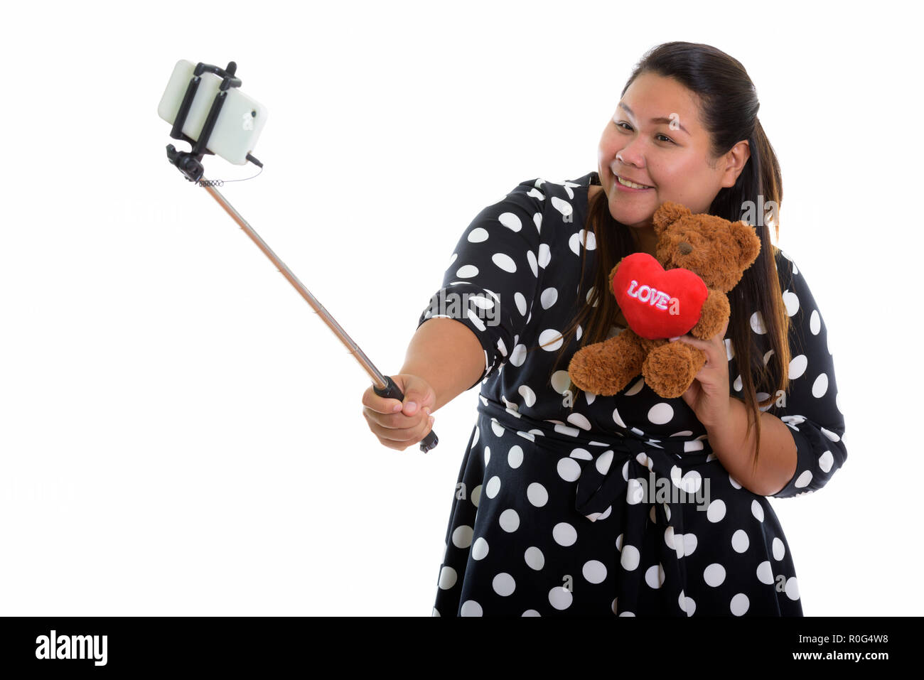 Studio shot of young woman smiling Asian fat heureux tout en maintenant Banque D'Images