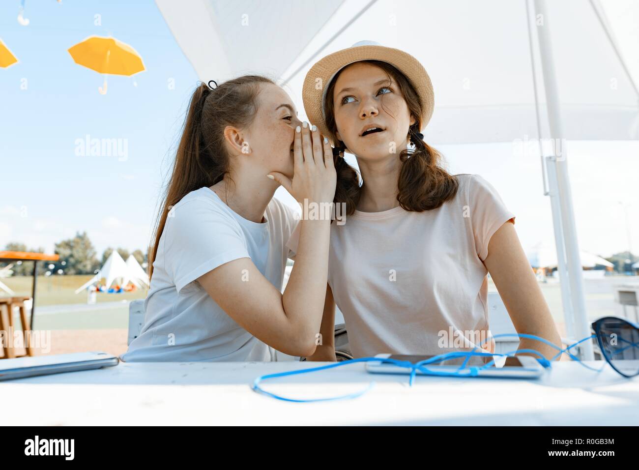 Pour les adolescents de s'amuser, parler, rire, secret. S'asseoir dans un café de la rue, journée ensoleillée dans les loisirs et de divertissement, de style de vie des jeunes. Banque D'Images