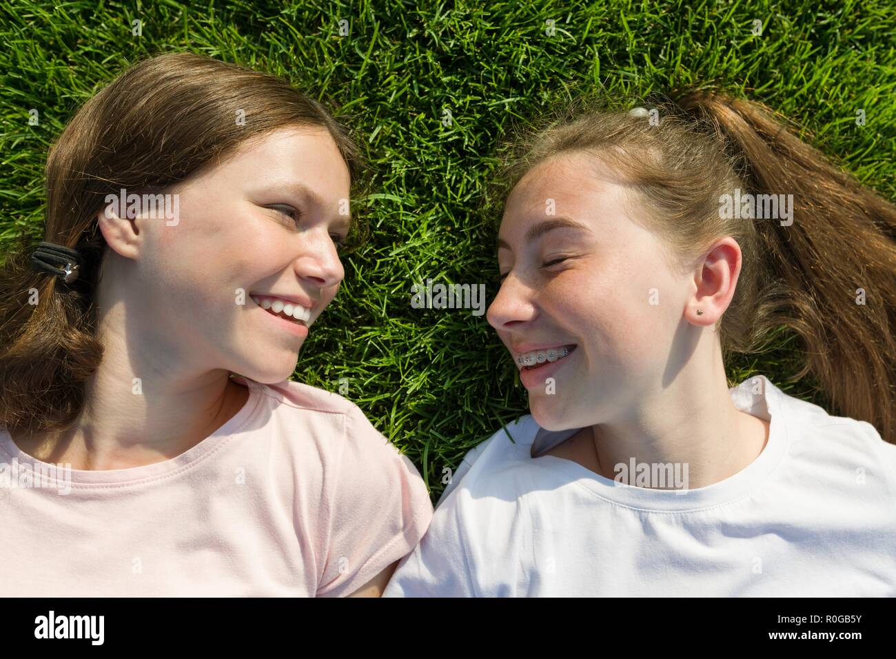 Face Close-up of young teen girls, vu de dessus, les filles se coucher sur l'herbe verte. Banque D'Images