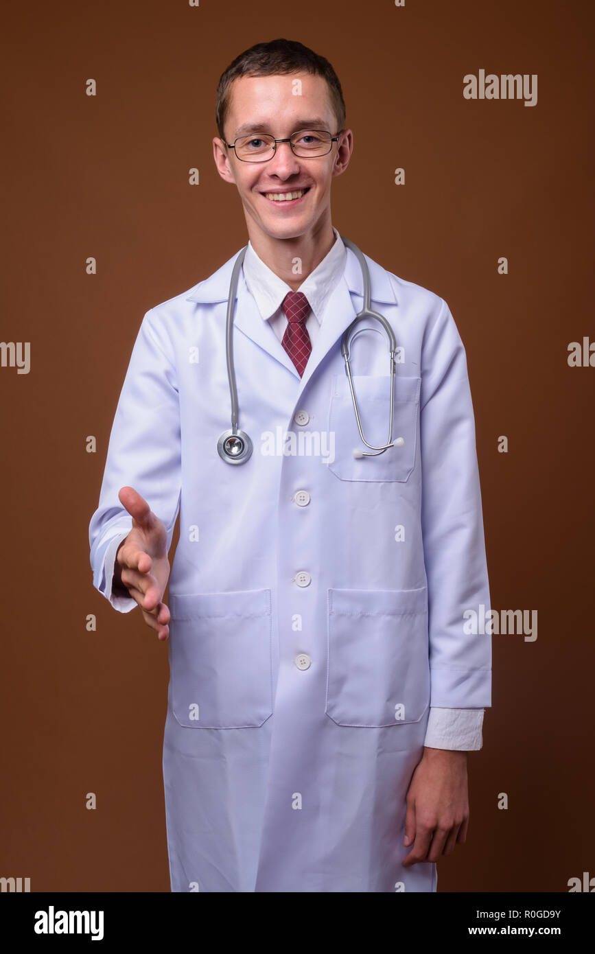 Portrait de jeune homme médecin contre fond brun Banque D'Images