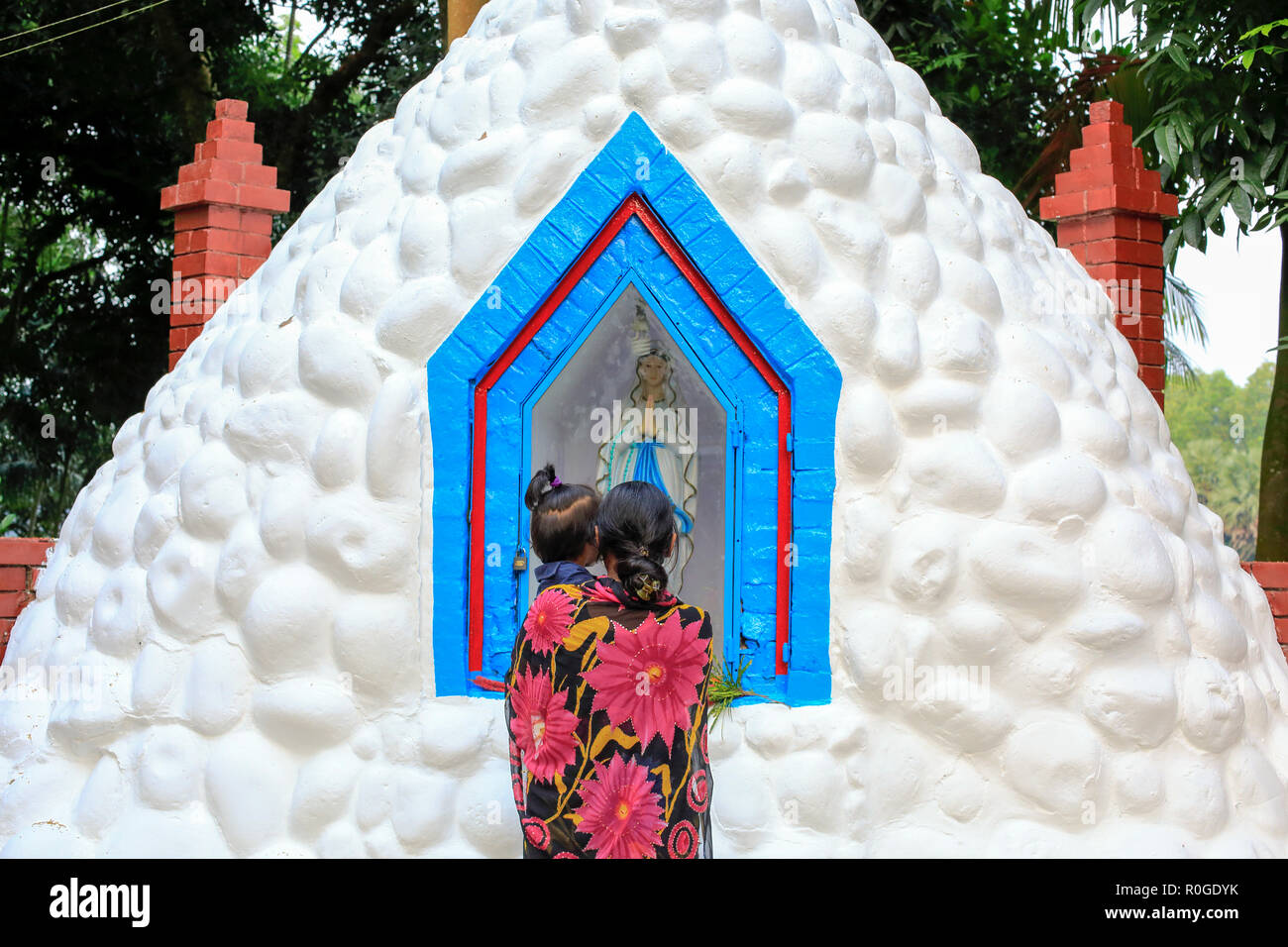 Une femme catholique prie devant la statue de Mère Marie Saint John's Church dans le Tumulia Gazipur, couverte de fleurs d'observer tous les jours des morts, Banque D'Images