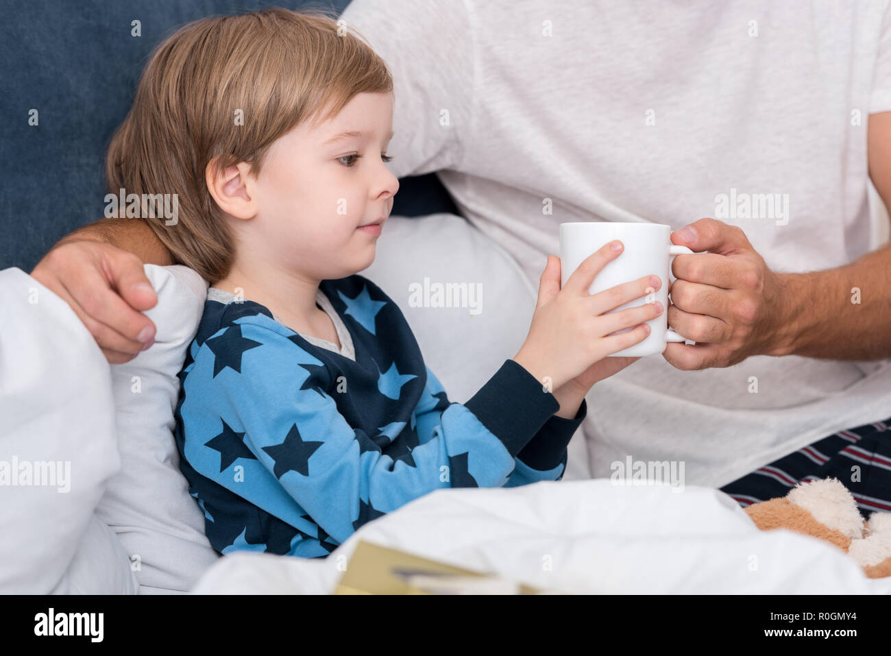 Cropped shot of father giving tasse de boisson chaude à son fils au lit Banque D'Images