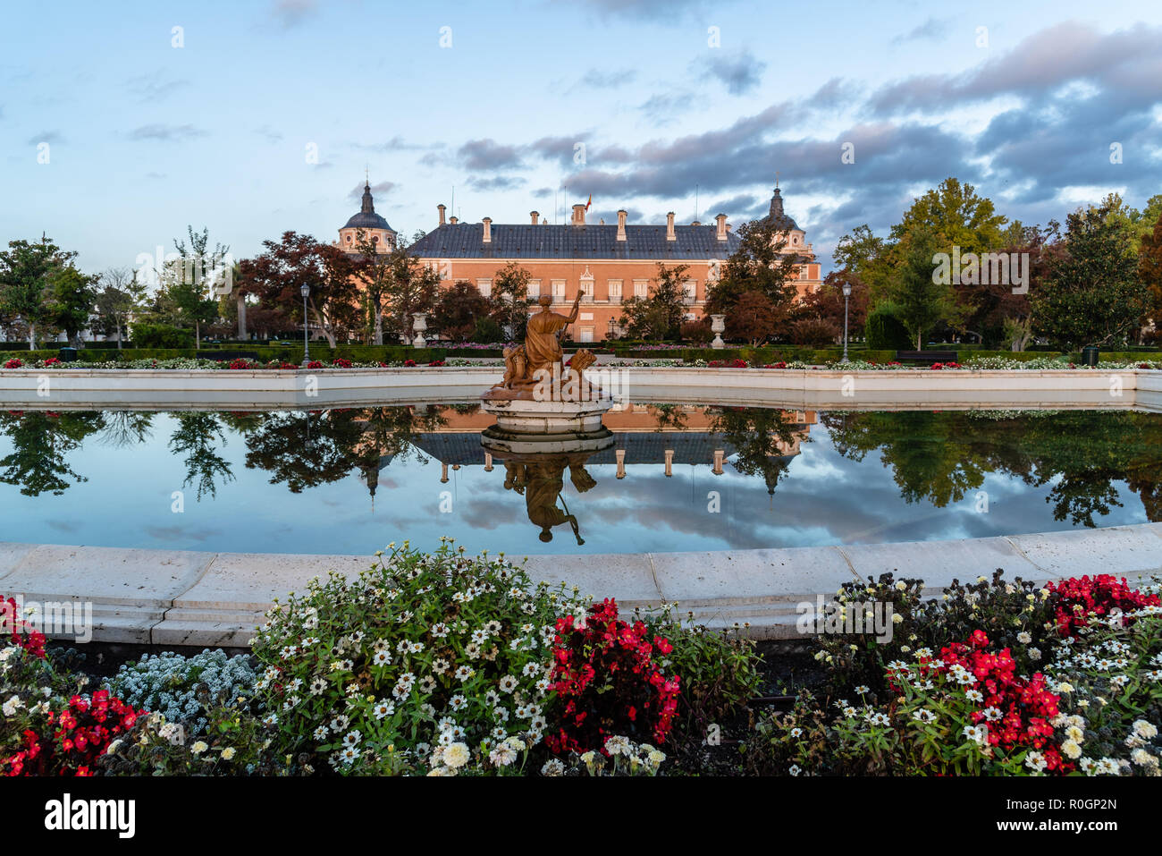 Aranjuez, Espagne - 20 octobre 2018 : Palais Royal d'Aranjuez et la réflexion sur l'eau de la fontaine dans le jardin Parterre au lever du soleil. Il s'agit d'une résidence de t Banque D'Images