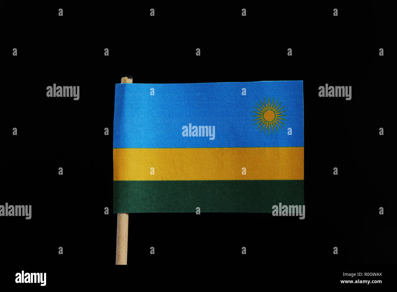 Un drapeau officiel du Rwanda le cure-dent sur fond noir. Un drapeau tricolore horizontal de bleu, jaune et vert avec du jaune soleil en champ bleu. Banque D'Images