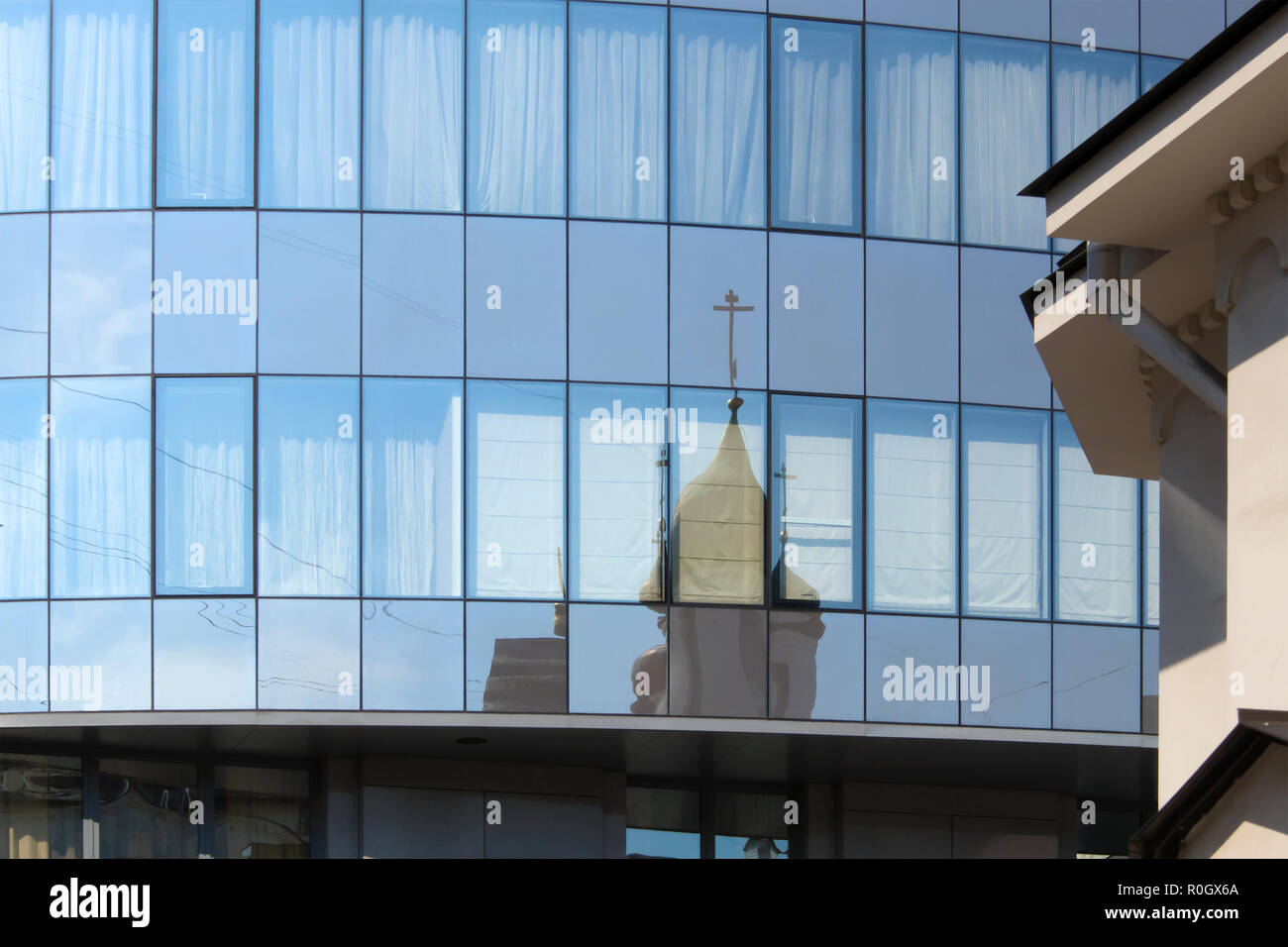 Reflet déformé de la vieille cathédrale orthodoxe dans les fenêtres des bâtiments de la ville moderne Banque D'Images