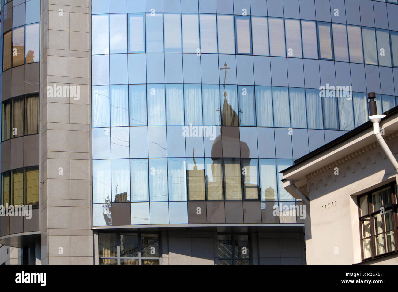 Reflet déformé de la vieille cathédrale orthodoxe dans les fenêtres des bâtiments de la ville moderne Banque D'Images