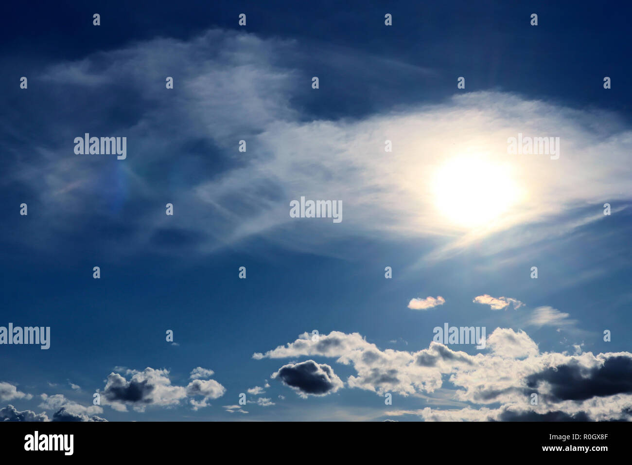 Soleil clair avec l'auréole à travers les nuages cirrus contre le ciel bleu Banque D'Images