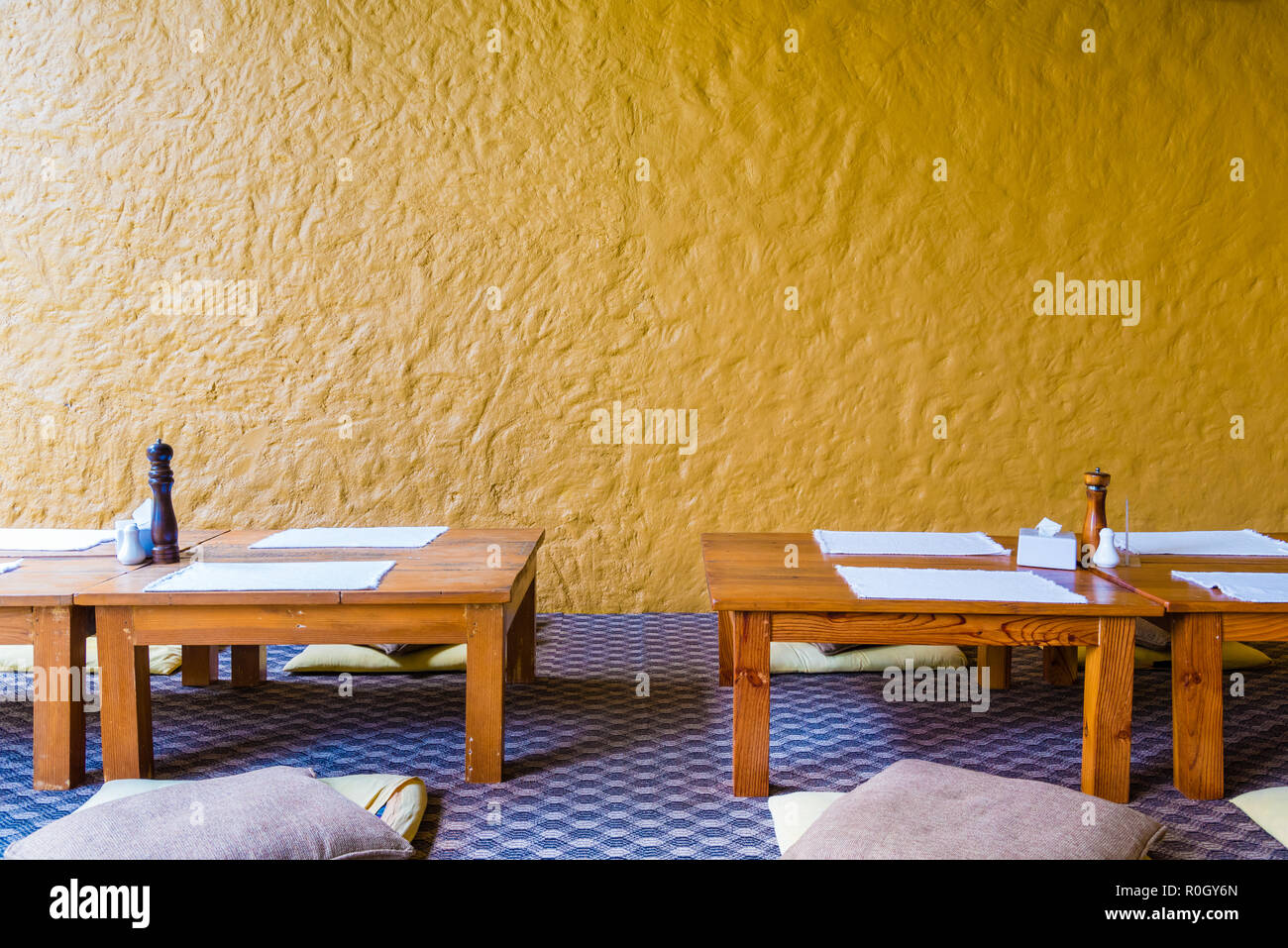 S'asseoir sur le plancher bas table à manger au restaurant avec mur jaune  en arrière-plan Photo Stock - Alamy