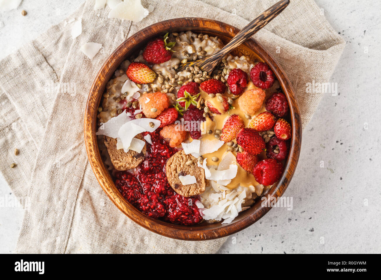 Vegan Trendy bol de gruau d'avoine aux fruits rouges, végétalien premières balles et le beurre d'arachide dans un bol en bois, vue du dessus. Banque D'Images