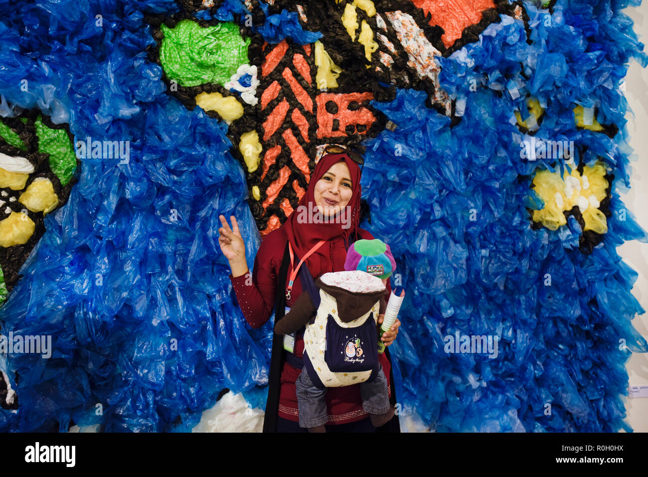 Femme d'Afrique du Nord et son bébé posant devant une carte du monde faite de sacs en plastique recyclé à la Conférence des Nations Unies sur les changements climatiques Banque D'Images